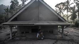 Seorang pria duduk di depan sebuah rumah yang terendam lumpur setelah letusan gunung berapi oleh Gunung Semeru di desa Kajar Kuning di Lumajang (5/12/2022). Gunung Semeru meletus pada tanggal 4 Desember memuntahkan awan abu panas setinggi satu mil dan sungai lava di sisinya sambil memicu evakuasi hampir 2.000 orang tepat satu tahun setelah letusan besar terakhirnya menewaskan puluhan orang. (AFP/Juni Kriswanto)