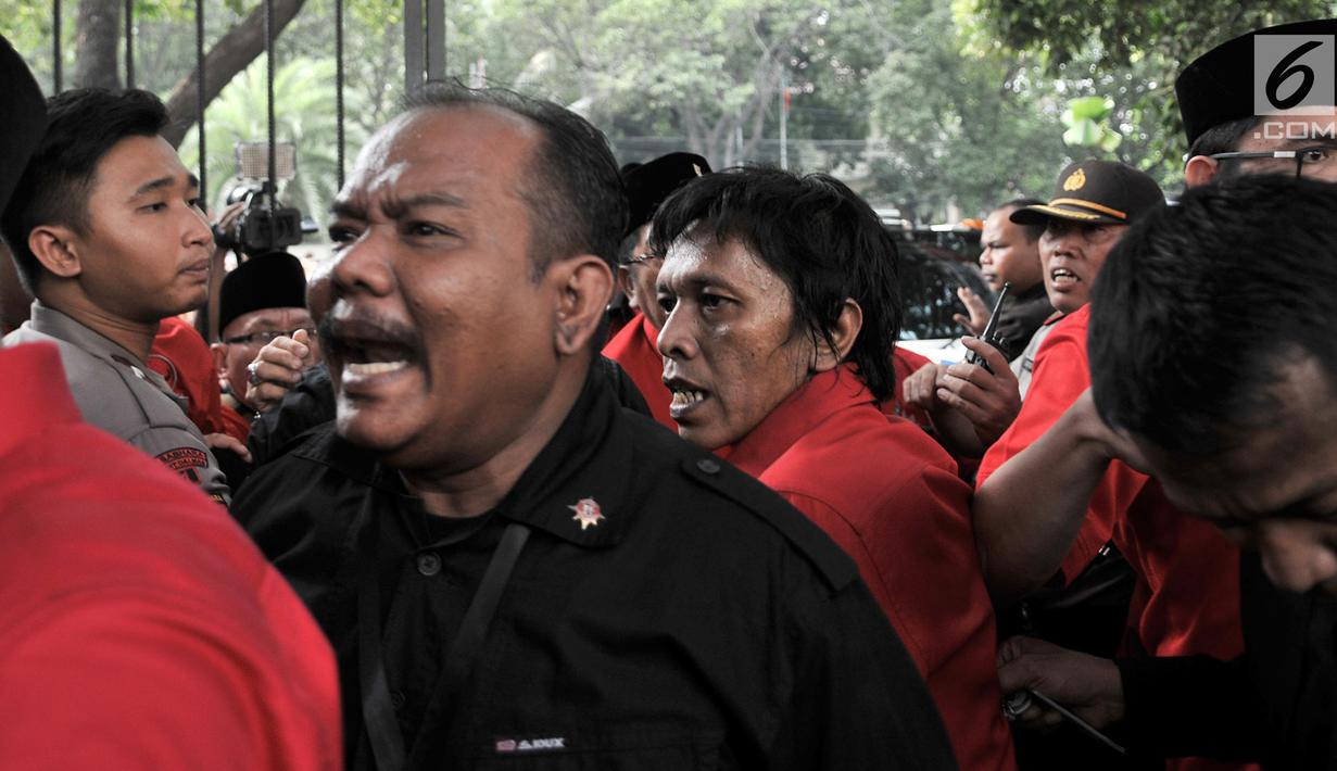 Kader PDIP Adian Napitupulu saling dorong dengan petugas saat hendak masuk ke Gedung KPU, Jakarta, Selasa (17/7). Elite serta massa PDIP terlibat kericuhan saat hendak mengantarkan pengurus DPP mendaftarkan bakal caleg. (Merdeka.com/ Iqbal S. Nugroho)