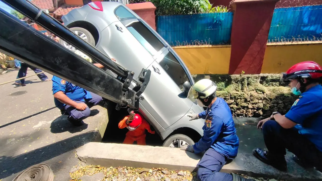 Petugas Damkar mengevakuasi mobil yang terpersok ke selokan di Jalan Pembaharuan, Kelapa Dua Wetan, Ciracas, Jakarta Timur