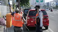 Petugas Dishub mengawasi pelanggar aturan Pembatasan Sosial Berskala Besar saat menyapu jalan di Tanah Abang, Jakarta, Jumat (15/5/2020). Pemprov DKI memberlakukan sanksi sosial bagi pelanggar PSBB dengan memakaikan rompi bertulis ‘Pelanggar PSBB’ saat menyapu jalan. (Liputan6.com/Faizal Fanani)