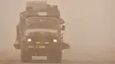 <p>Sebuah truk melaju melalui badai pasir Musim Semi di kota Nasiriyah, di provinsi Dhi Qar, Irak selatan (5/5/2022). Irak kembali diselimuti lapisan jingga tebal karena mengalami serangkaian badai debu terbaru yang semakin sering terjadi. (AFP/Asaad Niazi)</p>