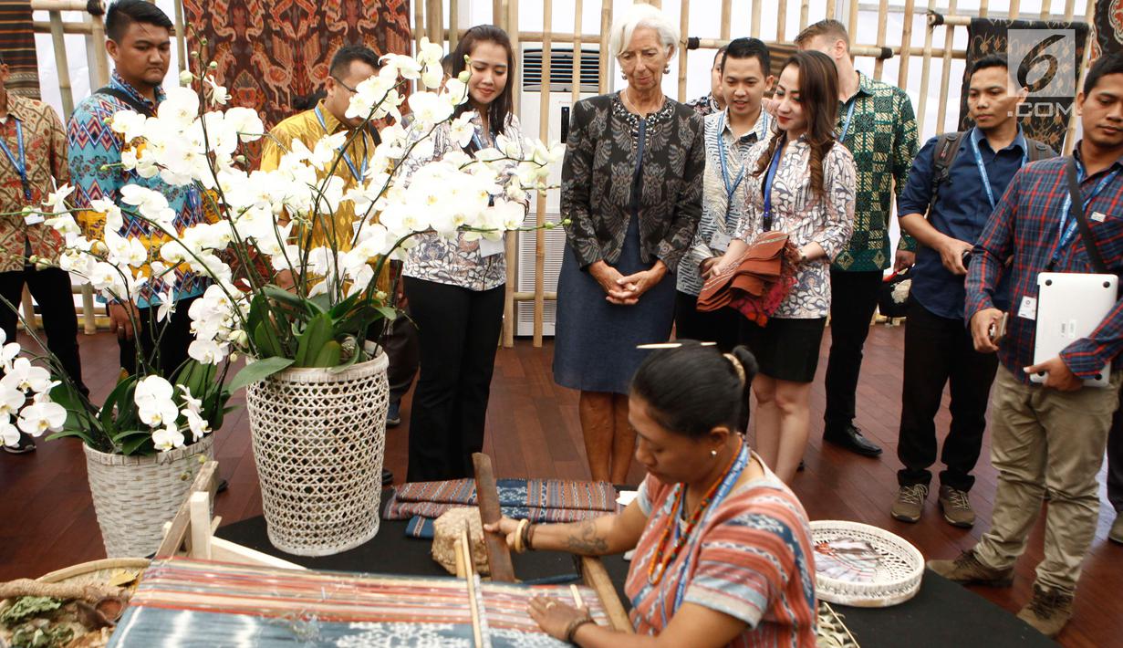 Managing Director IMF Christine Lagarde menyaksikan cara menenun saat berkunjung ke Paviliun Indonesia di arena pertemuan IMF-Bank Dunia, Bali, Rabu (10/10). Christine antusias melihat ragam potensi Indonesia yang dipamerkan. (Liputan6.com/Angga Yuniar)