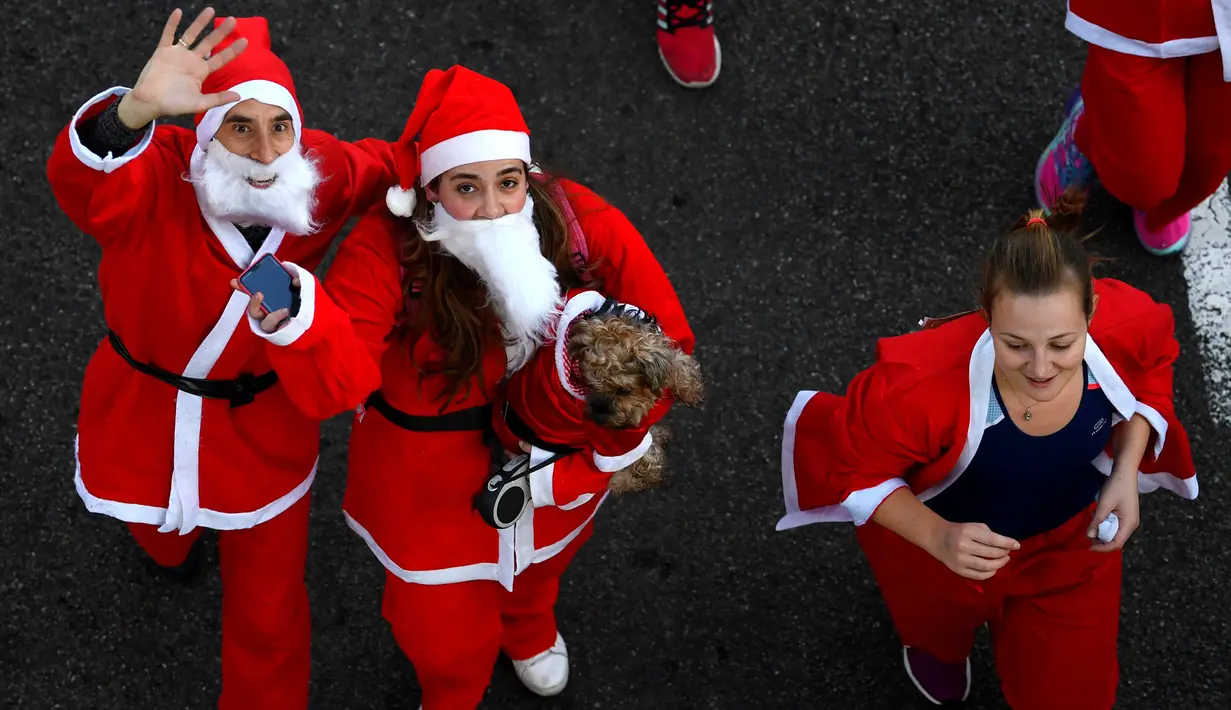 Peserta berkostum Sinterklas melambaikan tangan saat mengikuti Santa Claus Run di Madrid, Spanyol, Minggu (9/12). Ribuan orang berjalan dan berlari dalam perlombaan Santa tahunan melintasi jalan-jalan ibu kota Spanyol. (Gabriel BOUYS / AFP)