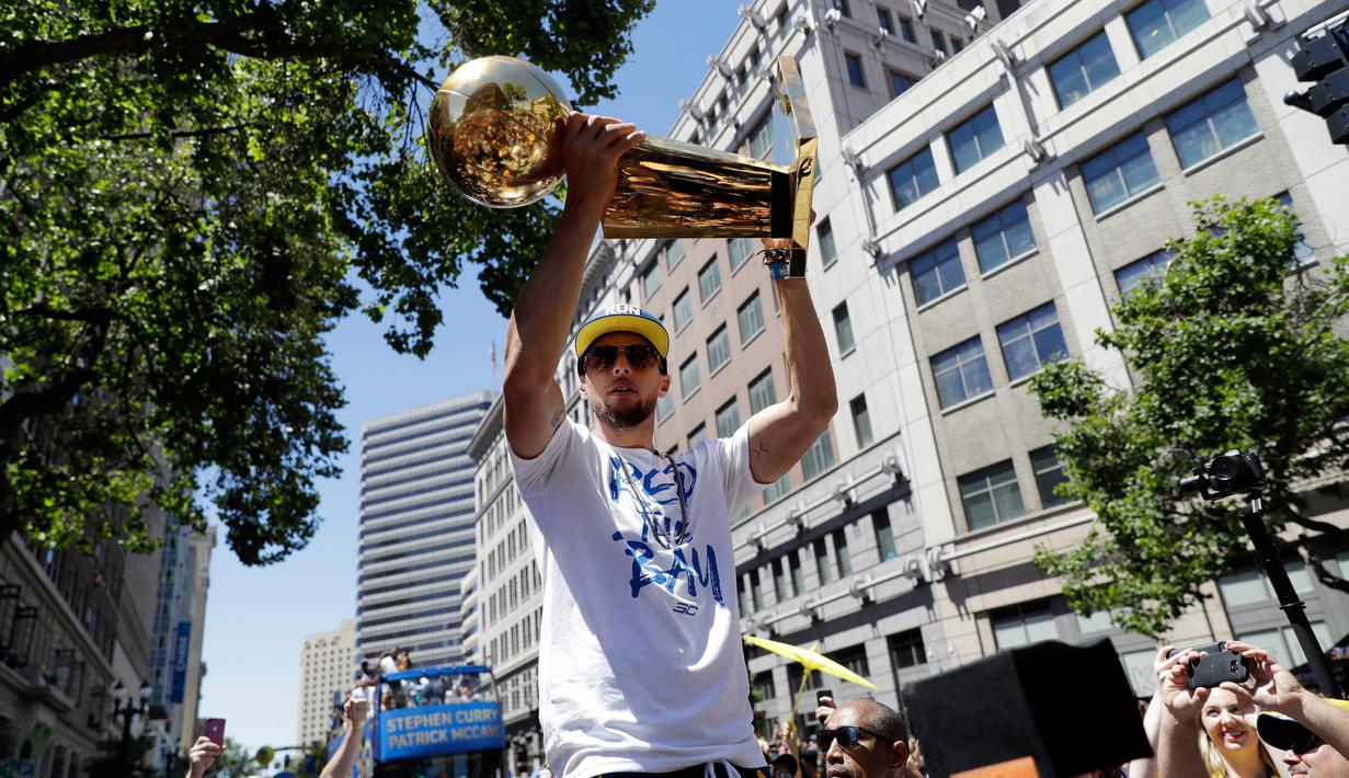 Pemain Guard Golden State Warriors, Stephen Curry menunjukkan tropi Larry O'Brien saat menggelar parade Warriors 2018 usai menjuarai NBA 2018 di pusat kota Oakland, California, Amerika Serikat, (12/6). (AP Photo/Marcio Jose Sanchez)