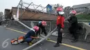Petugas pemadam kebakaran membantu evakuasi Jembatan Penyeberangan Orang (JPO) yang roboh usai ditabrak truk trailer di KM 7.600 Tol BSD, Tangsel, Senin (16/5). Dua unit mobil crane digunakan untuk membantu evakuasi. (Liputan6.com/Helmi Afandi)