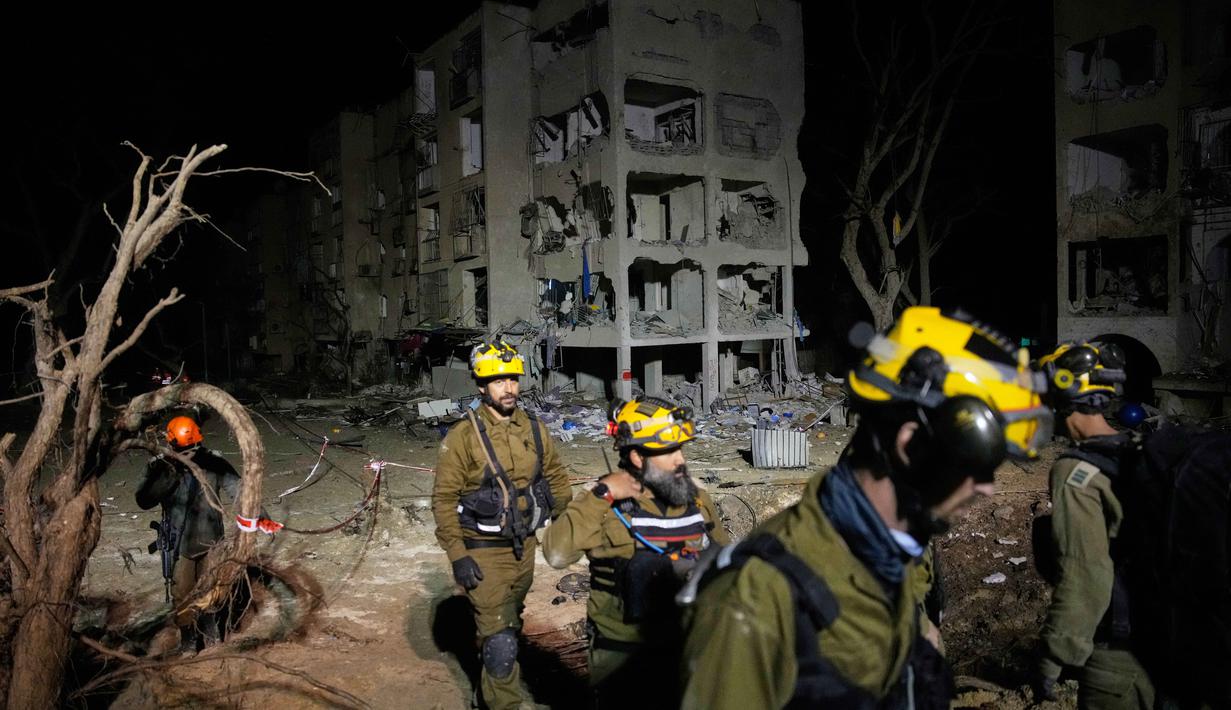 Serangan ini merupakan bagian dari eskalasi besar Iran yang menargetkan kota Dimona, yang berdekatan dengan fasilitas nuklir. Tampak dalam foto, pasukan keamanan Israel dan tim penyelamat bekerja di lokasi yang dihantam rudal Iran di Arad, Israel Selatan, Minggu, 22 Maret 2026. (AP Photo/Ohad Zwigenberg)