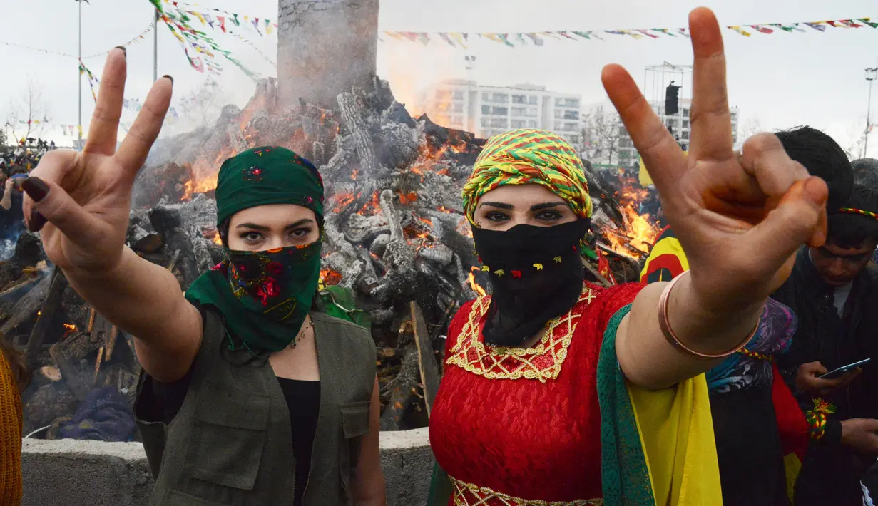 Dua wanita Kurdi Turki menunjukkan simbol perdamaian selama Perayaan Newroz di Diyarbakir, Turki (21/3). Festival ini untuk memperingati hari pertama musim semi, yang jatuh setiap tanggal 21 Maret. (AFP Photo / Ilyas Akengin)