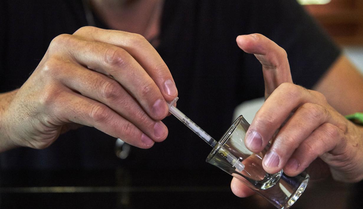 Steve Ludwin memindahkan bisa ular viper palem ke dalam jarum suntik untuk digunakan olehnya, di Kennington, London, Kamis (9/11). Steve Ludwin sudah hampir 30 tahun menyuntikkan bisa ular viper tersebut ke tubuhnya. (AFP Photo/Niklas Halle'n)