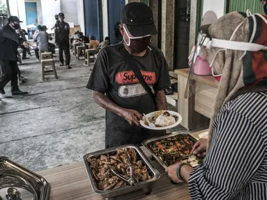 Warga mengambil makanan gratis di Jalan Basuki Rachmat, Cipinang Muara, Jakarta, Senin (8/3/2021). Sejak Juli 2020, Hadi (40) dibantu teman-temannya menggelar layanan makan gratis kepada warga