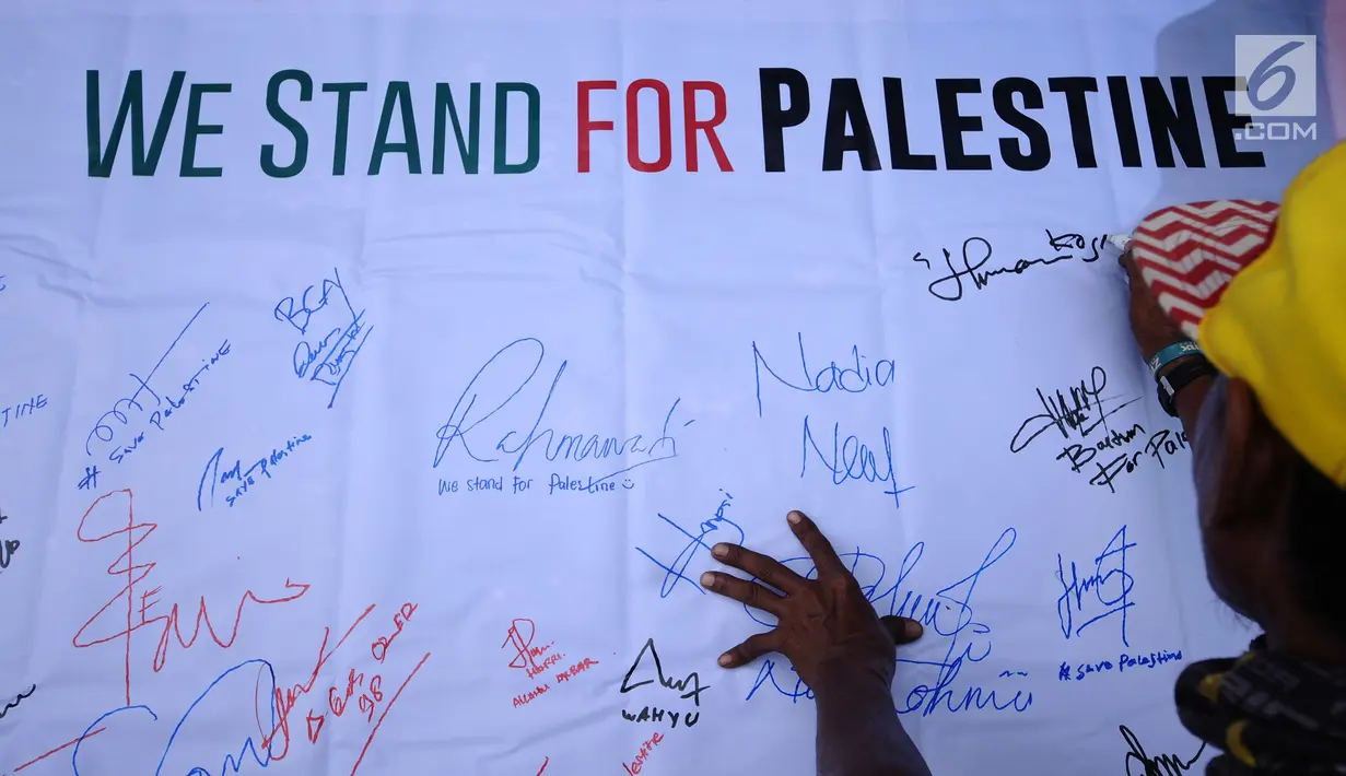 Warga menandatangani spanduk dukungan bagi negara Palestina di kawasan Bundaran HI, Jakarta, Minggu (10/12). Mereka memprotes keputusan Presiden AS Donald Trump yang mengakui Yerusalem sebagai Ibu Kota Israel. (Liputan6.com/Helmi Fithriansyah)