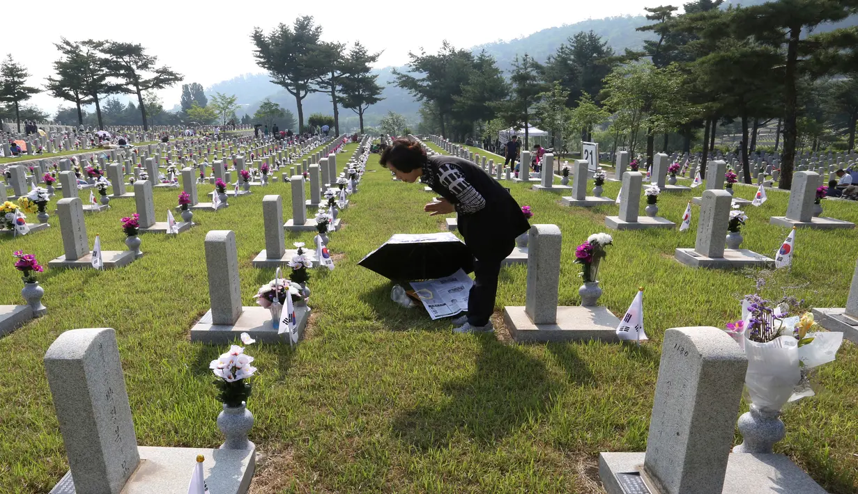 Warga Korea Selatan, Kim Soon berdoa di depan batu nisan ayahnya yang meninggal selama Perang Korea di pemakaman nasional, Seoul, Korea Selatan, Rabu (6/6). Kegiatan ini dilakukan dalam Memorial Day. (AP Photo/Ahn Young-joon)