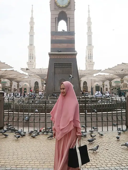 Gaya hijab syar'i berwarna pink salmon ini membuat Melody semakin anggun. Senyumannya yang tenang tidak pernah pudar. (Liputan6.com/IG/@melodylaksani92)