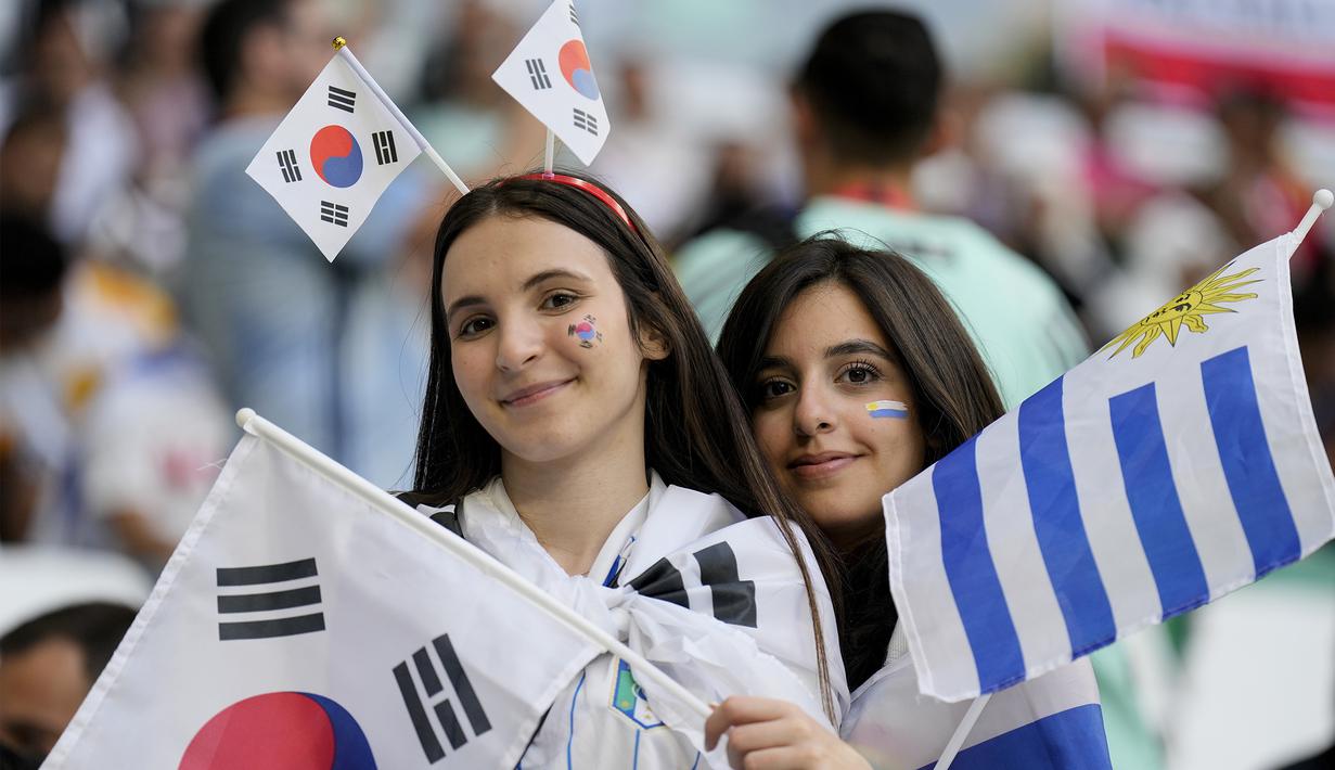 Suporter wanita Korea Selatan juga berbaur dengan suporter Uruguay. Itu terlihat saat keduanya berpose bersama sebelum laga dimulai. (AP Photo/Martin Meissner)