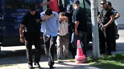 Dua dari 8 perwira militer pendukung kudeta Turki menutupi wajahnya, di Alexandroupoli, utara Yunani, Minggu (17/7). 8 pria yang terbang dengan helikopter militer Turki itu ditahan petugas keamanan Yunani karena masuk secara ilegal. (Sakis MITROLIDIS/AFP)