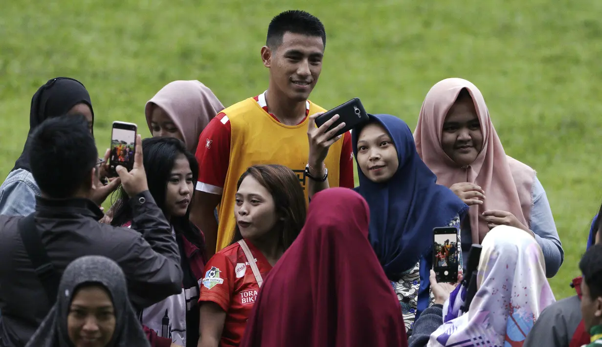 Pemain Arema FC, Hanif Sjahbandi, foto bersama dengan fans usai sesi latihan di Stadion Gajayana, Malang, Kamis (11/4). Setelah sesi latihan, pemain Arema FC melayani permintaan fans untuk foto bersama. (Bola.com/Yoppy Renato)
