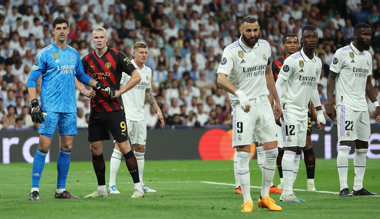 Pemain Manchester City, Erling Haaland mendapatkan pengawalan dari kiper Real Madrid, Thibaut Courtois pada laga leg pertama semifinal Liga Champions 2022/2023 di Santiago Bernabeu, Madrid, Rabu (10/05/2023) WIB. Laga berakhir dengan skor 1-1. (AFP/Oscar Del Pozo)