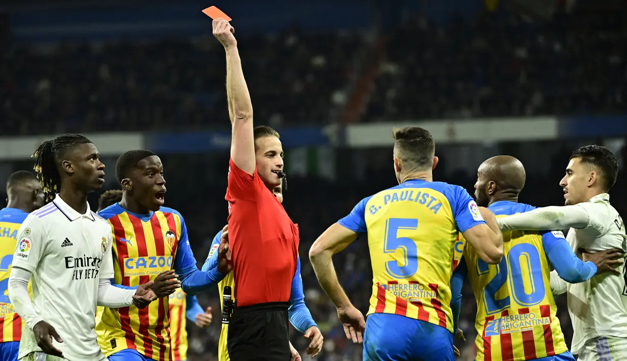 Wasit Javier Alberola Rojas memberikan kartu merah kepada pemain Valencia, Gabriel Paulista saat melawan Real Madrid pada laga Liga Spanyol di Stadion Santiago Bernabeu, (2/2/2023). Real Madrid meraih kemenangan penting pada pekan ke-17 Liga Spanyol 2022/2023. (AFP/Javier Soriano)