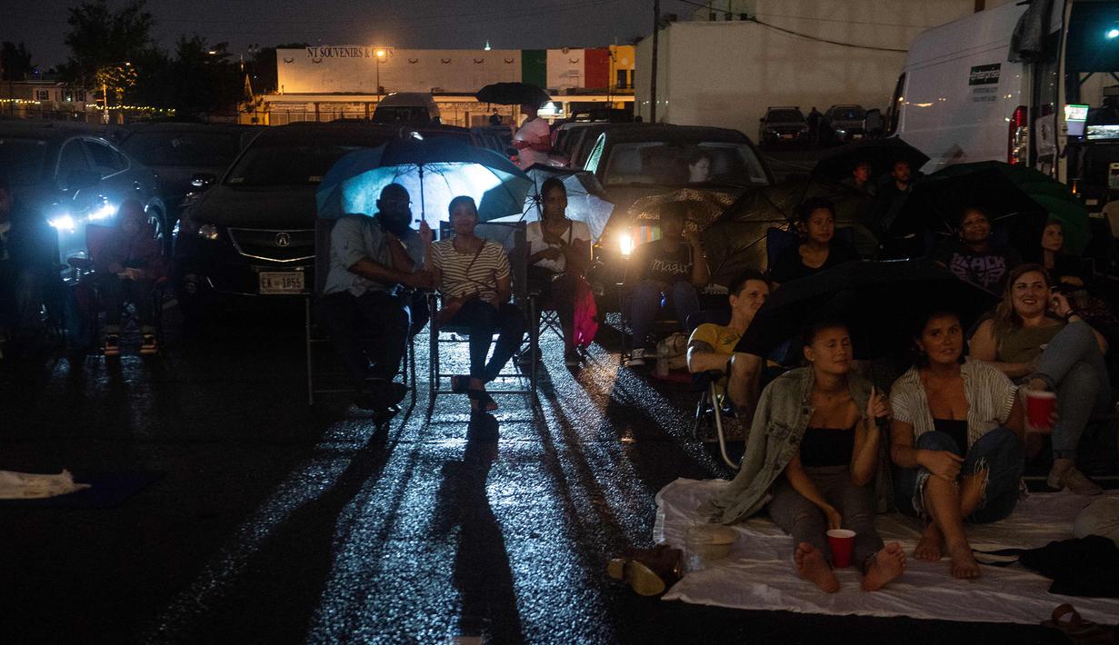 Orang-orang menonton film di luar ruangan saat pemutaran film drive-in di Union Market, Washington, 3 Agustus 2018. Walaupun antusiasme warga menurun, kini Drive-In atau menonton film di luar ruangan kembali bangkit. (AFP PHOTO/Nicholas Kamm)
