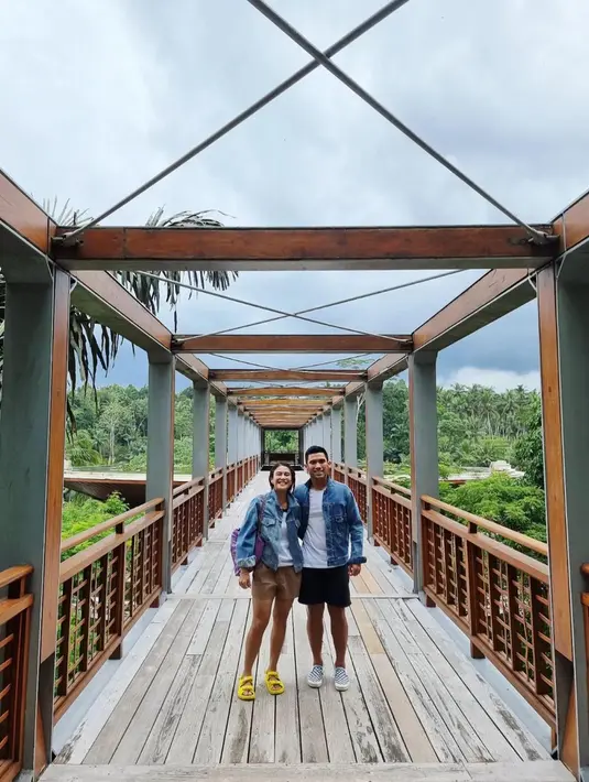 Wanita usia 40 tahun dan suaminya tampak mengenakan baju yang senada sambil tersenyum berfoto di jembatan iconic di Ubud yaitu The Four Season Sayan. (Instagram/therealdisastr)