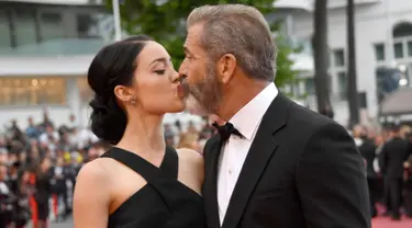 Aktor senior Mel Gibson mencium bibir pacar barunya, Rosalind Ross saat menghadiri acara penutupan Festival Film Cannes, Prancis, 22 Mei 2016.  Seperti yang diketahui, usia Mel Gibson dan kekasih cantiknya terpaut 35 tahun. (Anne-CHRISTINE POUJOULAT/AFP)