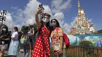 Para pengunjung yang mengenakan masker untuk mencegah penyebaran COVID-19 berswafoto di Disneyland Hong Kong, Kamis (18/6/2020). Disneyland Hong Kong kembali beroperasi pada 18 Juni 2020 dengan menerapkan sejumlah protokol kesehatan baru. (AP Photo/Kin Cheung)