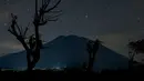 Pemandangan malam Gunung Agung di bawah langit penuh bintang terlihat dari Kubu di Karangasem, Bali, (28/9). Pihak berwenang berencana mengalihkan penerbangan jika terjadi erupsi Gunung Agung. (AFP Photo/Bay Ismoyo)