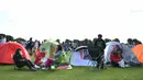 Sejumlah penonton beristirahat di tenda ketika mengantre untuk membeli tiket pada hari pertama turnamen tenis Kejuaraan Wimbledon 2019 di The All England Tennis Club di Wimbledon, London barat daya (1/7/2019). Turnamen ini dimulai 1 Juli-14 Juli 2019. (AFP Photo/Ben Stansall)