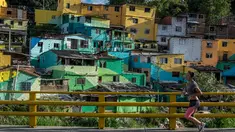 Seorang wanita berolahraga sambil menyusuri kawasan kumuh El Pesebre di pinggiran kota Medellin, Kolombia, 19 Juni 2017. Seniman Prancis, Tarik Bouanani melukis 230 rumah di kawasan tersebut membentuk mural raksasa. (JOAQUIN SARMIENTO/AFP)