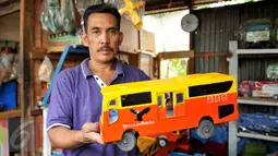 Pedagang menunjukkan mobil mainan berupa bus Transjakarta yang terbuat dari kayu di kios mainan di kawasan Pasar Minggu, Jakarta, Selasa (3/11). Membanjirnya mainan anak asal China mengancam produksi mainan dalam negeri. (Liputan6.com/Gempur M Surya)