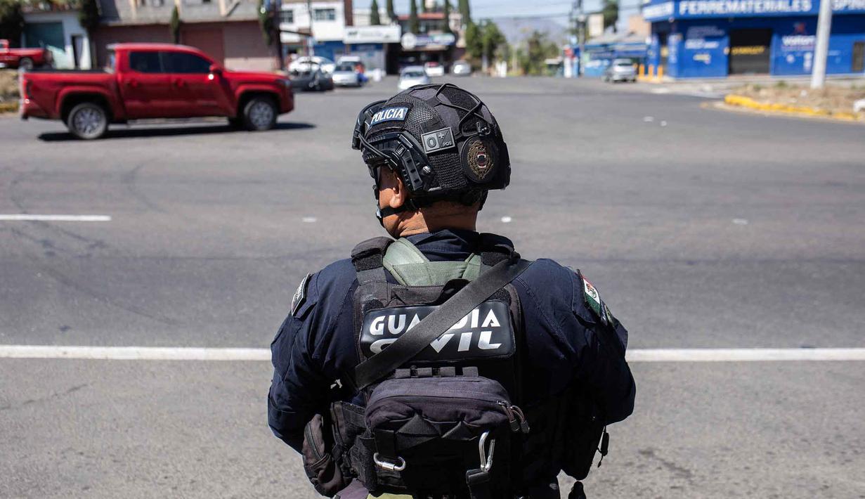 Seorang petugas polisi melakukan pemeriksaan keamanan di Jalan Raya Morelia-Patzcuaro untuk mencegah pembakaran kendaraan dan blokade jalan di negara bagian Michoacan, Meksiko, pada 23 Februari 2026. (Enrique Castro/AFP)
