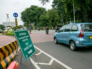 Taksi melintasi rambu lalu lintas pemberitahuan pengalihan jalan di kawasan Lapangan Banteng, Jakarta, Rabu (21/1/2021). Jalan Katedral akan ditutup selama proyek pembangunan terowongan silaturahmi Masjid Istiqlal-Gereja Katedral pada 20 Januari-31 Maret 2021. (Liputan6.com/Faizal Fanani)