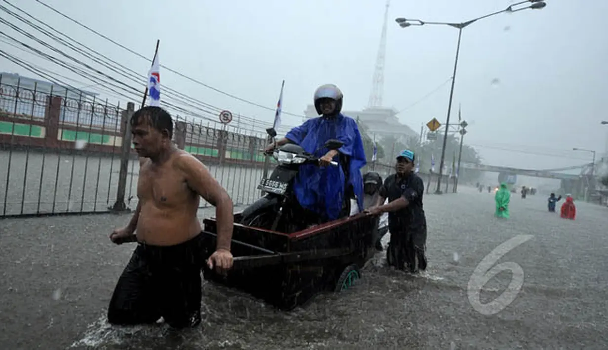 Seorang pengendara motor menggunakan jasa gerobak dorong untuk melewati banjir yang menggenangi jalan Gunung Sahari, Jakarta, Senin (9/2/2015).  (Liputan6.com/Faizal Fanani)