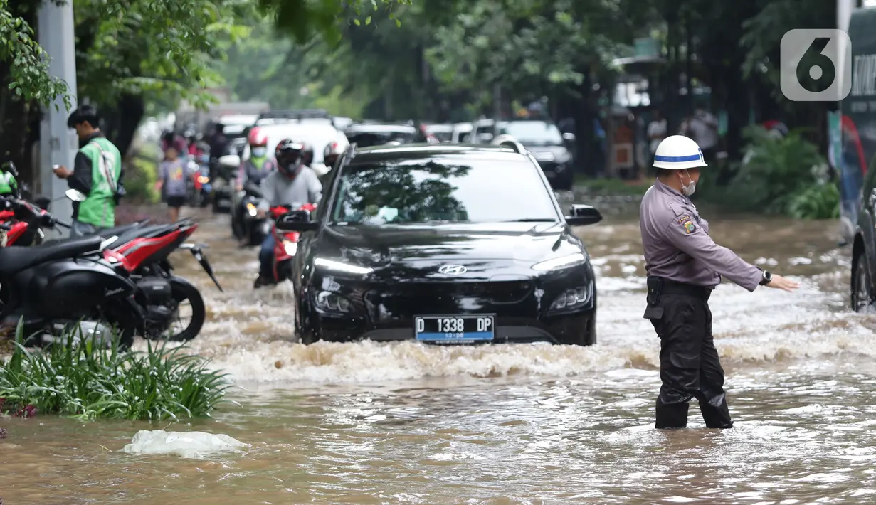 Petugas kepolisian terlihat saat kendaraan menerobos sebagian Jalan Bungur Besar Raya yang tergenang air, Jakarta, Selasa (18/1/2022). Genangan air membuat arus lalu lintas di sekitar depan PN Jakarta Pusat menjadi terganggu dan tersendat. (Liputan6.com/Helmi Fithriansyah)