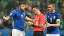 Pemain Italia, Leonardo Bonucci dan Andrea Barzagli, memprotes wasit Ovidiu Hategan pada laga Grup E Piala Eropa 2016 di Stade Pierre Mauroy, Lille, Kamis (23/6/2016) dini hari WIB. (AFP/Miguel Medina)