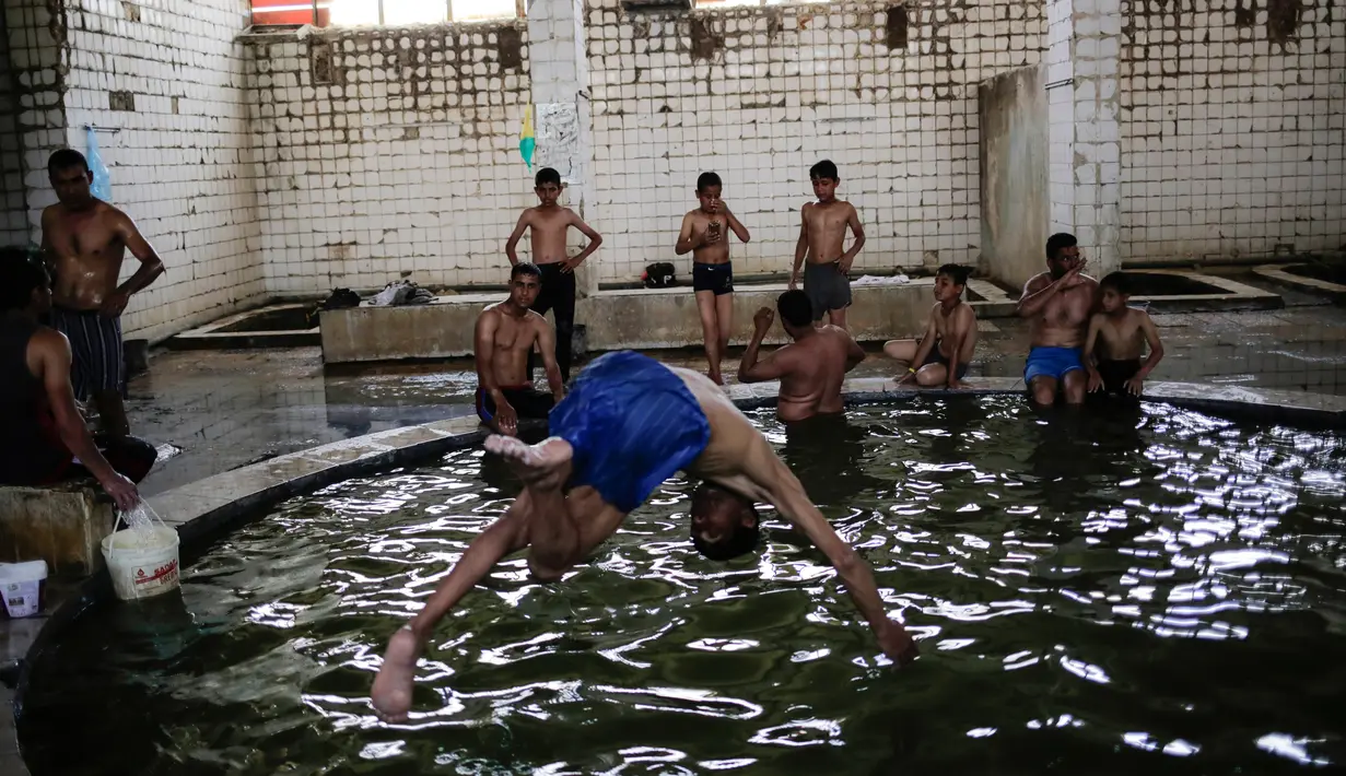 Sejumlah pengunjung saat berada di kolam renang air hangat dari belerang di Hamam Alli, Mosul, Irak, (27/4). Sebelum ISIS mengambil alih Hamam Alil pada 2014, warga Irak selalu mengunjungi spa bersejarah di selatan Mosul ini. (AP Photo/Bram Janssen)