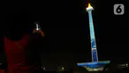 Pengunjung mengambil gambar video mapping dalam Monas Week 2023 di tugu Monumen Nasional (Monas), Jakarta Pusat, Jumat (29/12/2023). (Liputan6.com/Herman Zakharia)