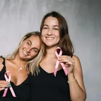 Dua wanita yang sedang memegang pita pink simbol kesadaran kanker payudara (Foto dok : pexels/Anntarazevich).