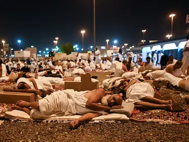 Jemaah haji beristirahat di Muzdalifah, Arab Saudi, Selasa (27/6/2023). Usai melaksanakan wukuf di Arafah, jemaah haji berangkat ke Muzdalifah untuk bermalam. (Sajjad HUSSAIN/AFP)