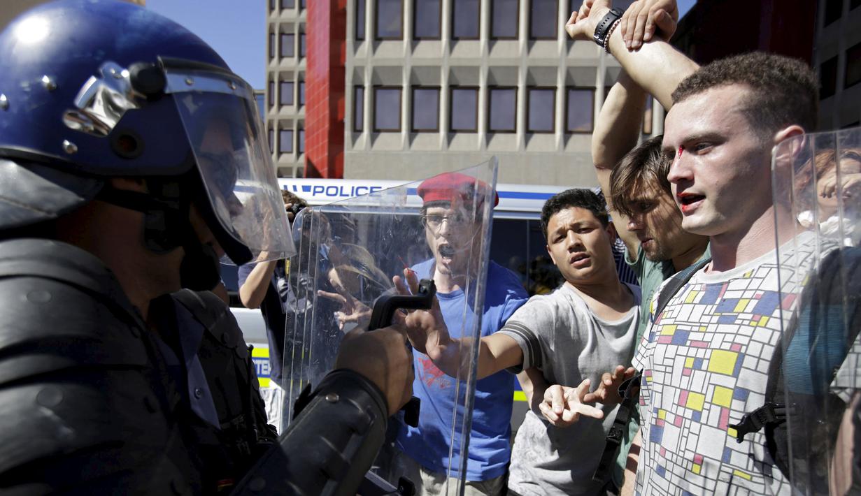 Polisi bentrok dengan pelajar di luar Parlemen Afrika Selatan di Cape Town, Rabu (21/10). Polisi anti huru hara menembakkan gas airmata kepada ratusan pelajar yang berdemonstrasi menentang rencana kenaikan uang sekolah. (REUTERS/Mark Wessels)