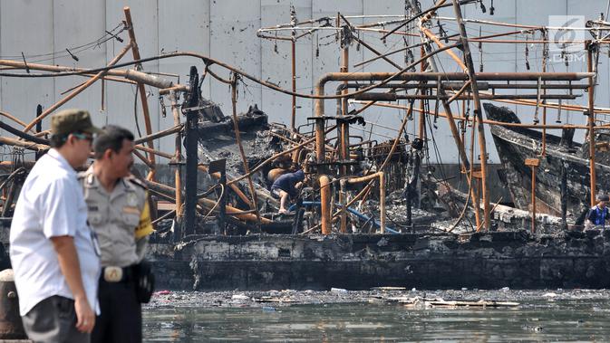 Polisi memantau proses pendinginan kapal yang ludes dilalap api di Pelabuhan Muara Baru, Jakarta, Minggu (24/2). Saat ini belum ada penetapan tersangka karena sejumlah saksi masih diperiksa. (Merdeka.com/Iqbal Nugroho)