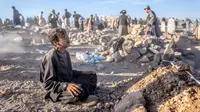 Seorang anak laki-laki berduka di samping makam adik laki-lakinya yang meninggal akibat gempa bumi di Distrik Zenda Jan, Provinsi Herat, sebelah barat Afghanistan, Senin (9/10/2023). Gempa mematikan yang terjadi pada Sabtu lalu menewaskan dan melukai ribuan orang serta menghancurkan rumah-rumah yang tak terhitung jumlahnya. (AP Photo/Ebrahim Noroozi)