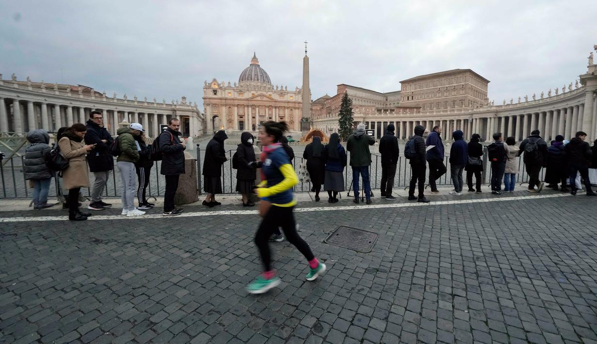 Orang-orang mengantre untuk memasuki Basilika Santo Petrus tempat mendiang Paus Emeritus Benediktus XVI disemayamkan di Vatikan, Senin (2/1/2023). Benediktus XVI, teolog Jerman yang akan dikenang sebagai paus pertama dalam 600 tahun yang mengundurkan diri, telah meninggal pada 31 Desember 2022 di usia 95 tahun. (AP Photo/Andrew Medichini)
