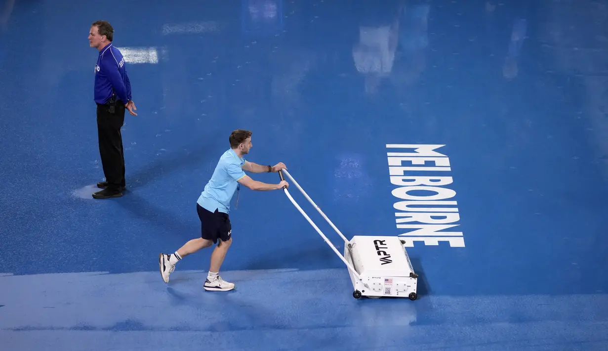 Staf mengeringkan lapangan saat hujan menunda pertandingan perempat final kejuaraan tenis Australia Open 2023 di Melbourne, Selasa (24/1/2023). Sejumlah laga di lapangan luar ruang terpaksa dihentikan saat hujan mengguyur termasuk laga perempat final tunggal putri antara petenis Latvia Jelena Ostapenko melawan petenis Kazakhstan Elena Rybakina. (AP Photo/Dita Alangkara)