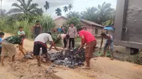 Personel Polres Rokan Hilir bersama masyarakat laksanakan gotong royong memperbaiki jalan menuju TPS pedalaman. (Liputan6.com/M Syukur)