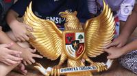 Anak-anak melihat lambang burung Garuda Pancasila di Kampung Pancasila, Karang Tengah, Kota Tangerang, Selasa (1/6/2021). Kegiatan tersebut antara lain seperti gotong royong membersihkan kampung dan sosialisasi penanaman nilai Pancasila kepada warga . (Liputan6.com/Angga Yuniar)