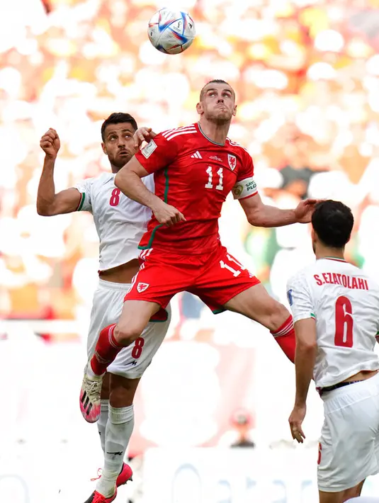 Pemain Iran Morteza Pouraliganji (kiri) berebut bola dengan pemain Wales Gareth Bale pada pertandingan sepak bola Grup B Piala Dunia 2022 di Stadion Ahmad Bin Ali, Al Rayyan, Qatar, Jumat (25/11/2022). Iran mengalahkan Wales dengan skor 2-0. (AP Photo/Francisco Seco)