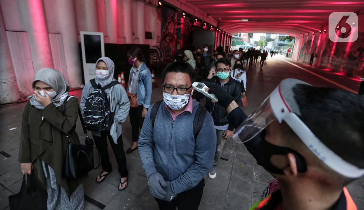 Petugas mengukur suhu tubuh calon penumpang sebelum memasuki stasiun Sudirman saat jam pulang kantor di Jakarta, Senin (8/6/2020). Aktivitas perkantoran dimulai kembali pada pekan kedua penerapan Pembatasan Sosial Berskala Besar (PSBB) transisi pandemi COVID-19. (Liputan6.com/Johan Tallo)