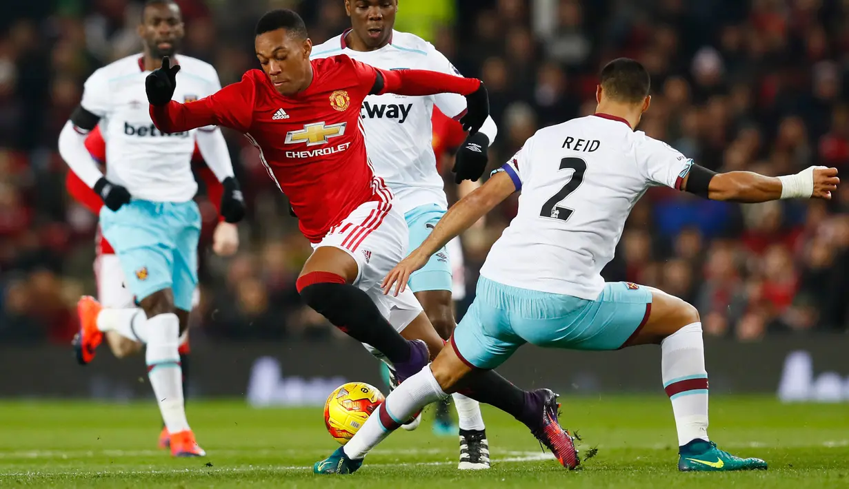 Penyerang MU, Anthony Martial (tengah) berusaha melewati bek West Ham United, Winston Reid di perempat final Piala Liga (EFL Cup) di Stadion Old Trafford, Inggris, (1/12). MU menang telak atas West Ham dengan skor 4-1. (Reuters/Jason Cairnduff)