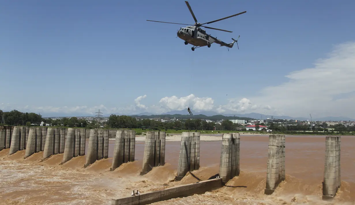 Prajurit Angkatan Udara India turun dari helikopter untuk menyelamatkan para nelayan yang terperangkap dalam banjir di Sungai Tawi di Jammu, India (19/8/2019). Permukaan air di banyak sungai di India utara meningkat setelah hujan lebat di musim hujan. (AP Photo/Channi Anand)