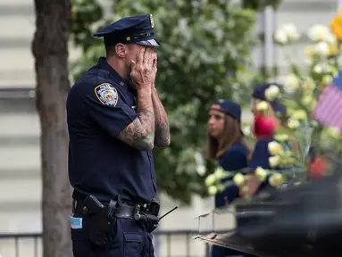 Petugas New York City Police Department (NYPD) mengusap wajahnya selama peringatan 16 tahun korban serangan 11 September di Museum dan Memorial Nasional 9/11, New York, Amerika Serikat, Senin (11/9). (Drew Angerer/Getty Images/AFP)